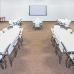 meeting space with 5 tables and 40 chairs and projector screen