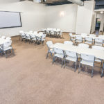 meeting space with 5 tables and 40 chairs and projector screen
